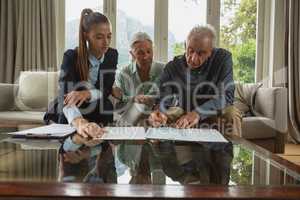 Active senior couple signing an agreement with real estate agent over documents in living room