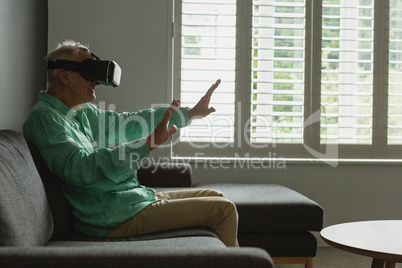 Active senior man using virtual reality headset in living room