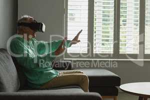 Active senior man using virtual reality headset in living room