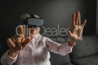 Active senior woman using virtual reality headset in living room