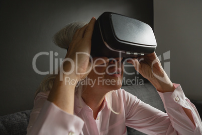 Active senior woman using virtual reality headset in living room