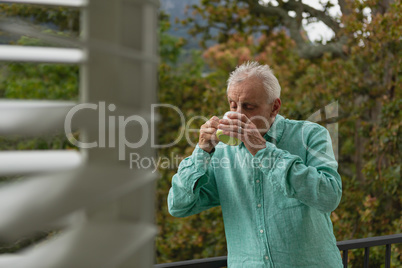 Active senior man drinking coffee on the balcony