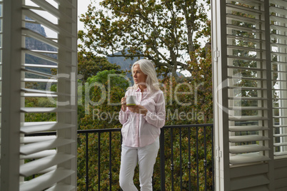 Active senior woman standing with coffee mug on the balcony