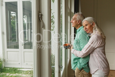 Active senior woman embracing senior man near door