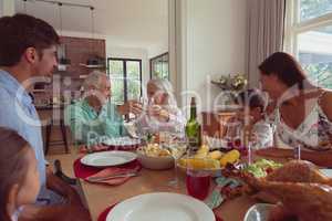 Multi-generation family toasting glasses of champagne on dining table at home