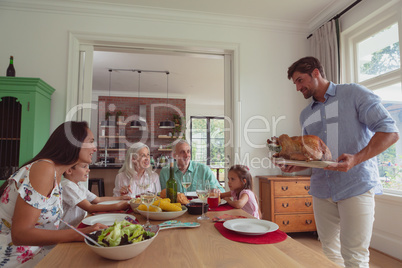 Multi-generation family having food on dining table at home