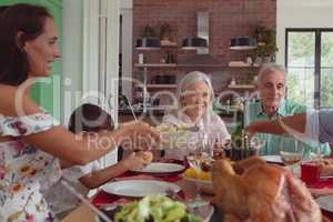Multi-generation family having food on dining table at home