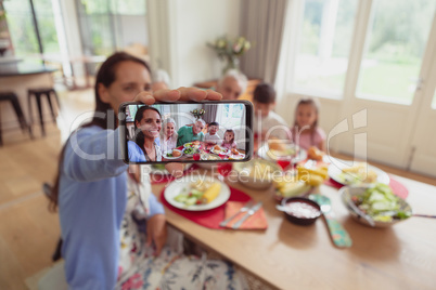 Multi-generation family taking selfie with mobile phone while having food on dining table