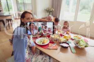 Multi-generation family taking selfie with mobile phone while having food on dining table