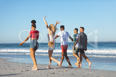 Group of friends walking together on the beach