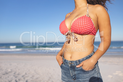 Woman in bikini standing with hands in pocket on the beach