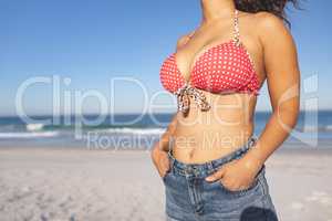 Woman in bikini standing with hands in pocket on the beach