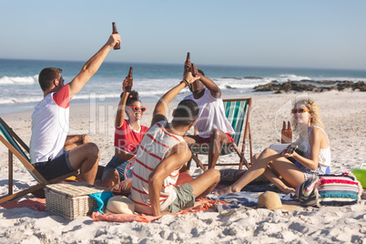 Group of friends toasting glasses of beer on the beach