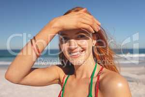 Happy redhead woman standing on the beach