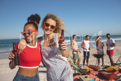 Group of female friends having beer on the beach