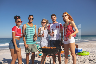 Group of friends having fun while preparing food on barbecue at beach