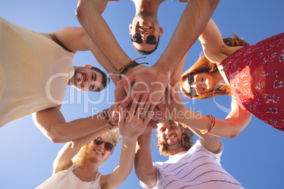 Group of friends forming hand stack on the beach