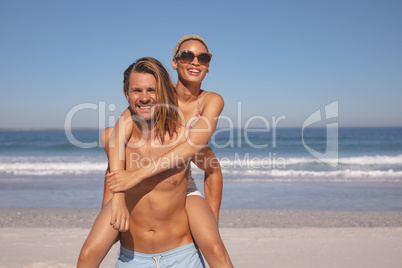 Man giving piggyback ride to woman on the beach
