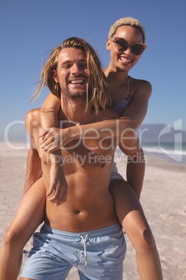 Man giving piggyback ride to woman on the beach