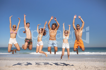 Group of friends jumping together on the beach