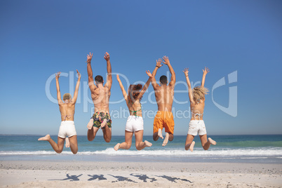 Group of friends jumping together on the beach