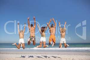 Group of friends jumping together on the beach