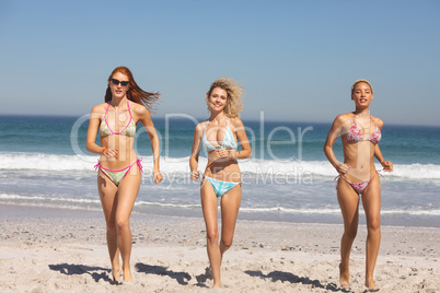 Group of female friends running together on the beach