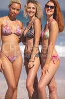 Female friends in bikini standing together on the beach