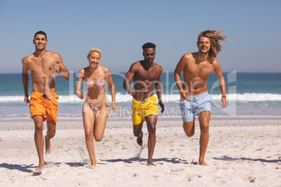 Group of friends running together on the beach