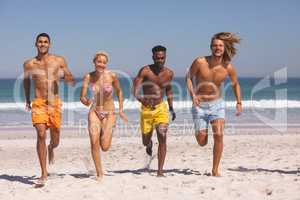 Group of friends running together on the beach