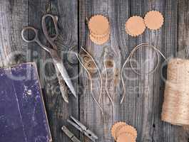 coil of brown rope, paper tags and old scissors on a gray wooden