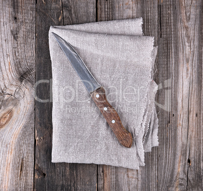 old kitchen knife on a gray napkin, wooden background