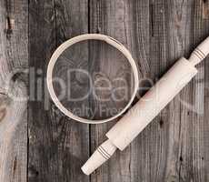 wooden rolling pin and a wooden round sieve on a gray table