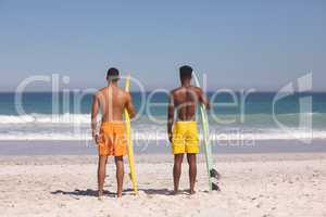 Male friends standing with surfboard on the beach