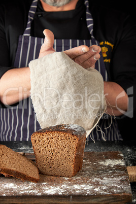 chef in black uniform sliced baked rye bread on a brown wooden b