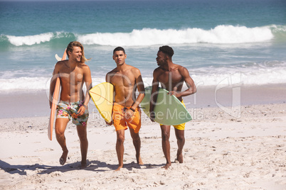 Male friends walking with surfboard on the beach