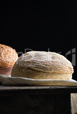 baked round white wheat bread on a textile towel, wooden old tab