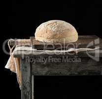 baked round white wheat bread on a textile towel, wooden old tab