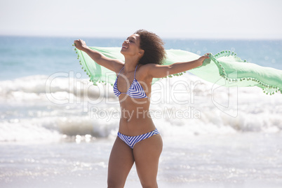 Woman in bikini with scarf standing on the beach