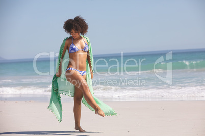 Woman in bikini with scarf standing on the beach