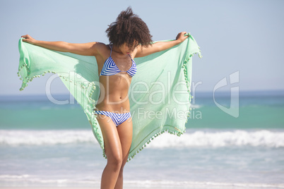 Woman in bikini with scarf standing on the beach