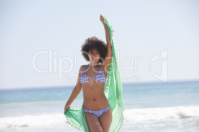 Woman in bikini with scarf standing on the beach