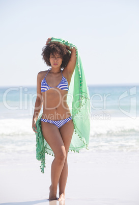 Woman in bikini with scarf standing on the beach