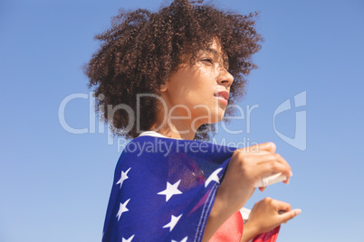Woman wrapped in american flag looking away on the beach