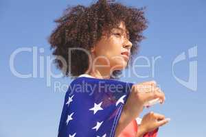 Woman wrapped in american flag looking away on the beach
