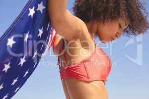 Woman in bikini holding american flag on the beach