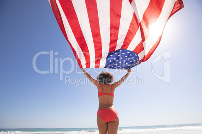 Woman in bikini holding american flag on the beach