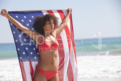 Woman in bikini holding american flag on the beach