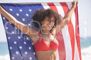 Woman in bikini holding american flag on the beach