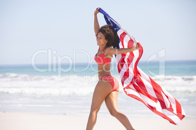 Woman in bikini with american flag walking on the beach